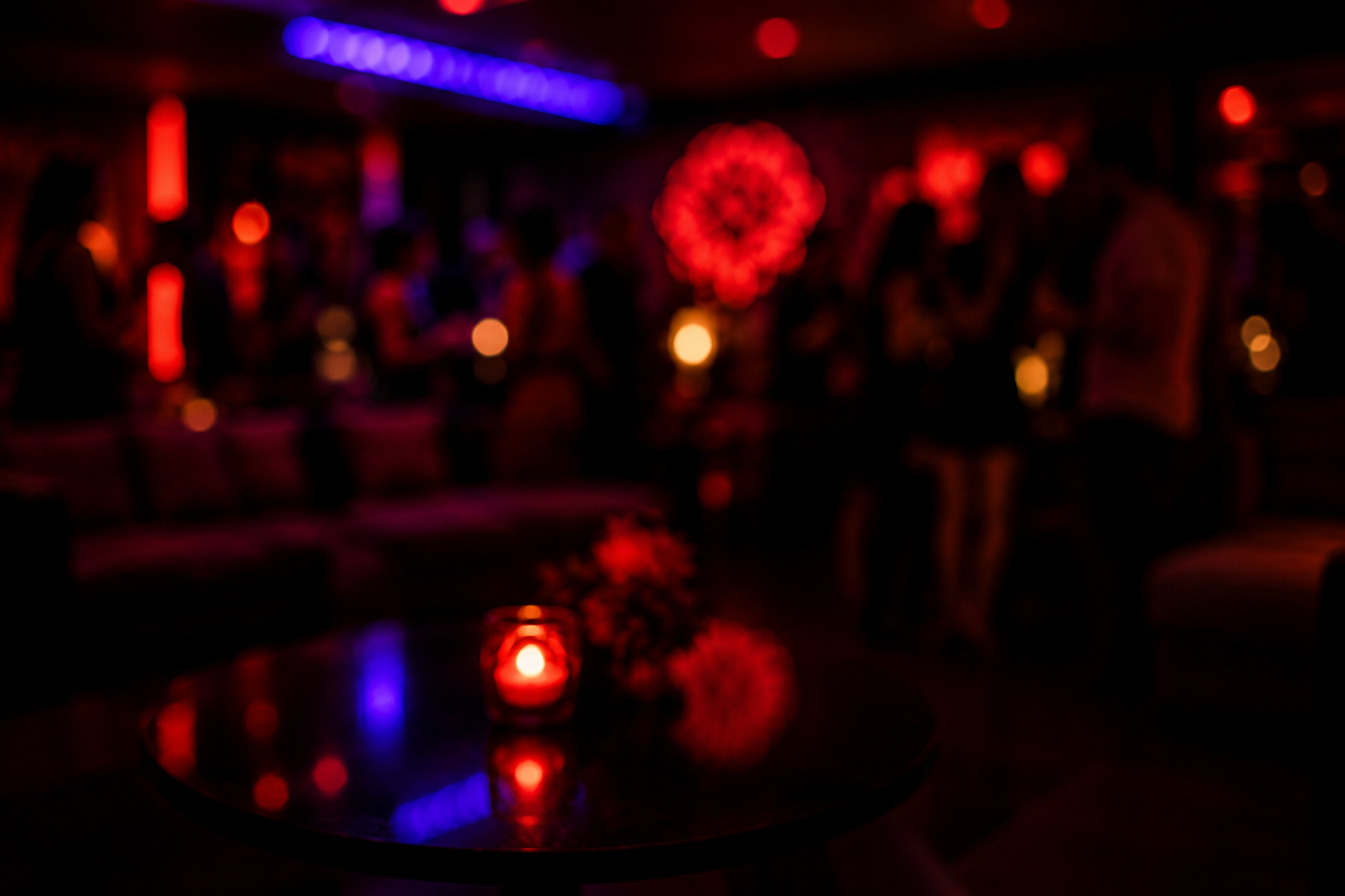 Low-lit lounge party with red glow and people in soft focus
